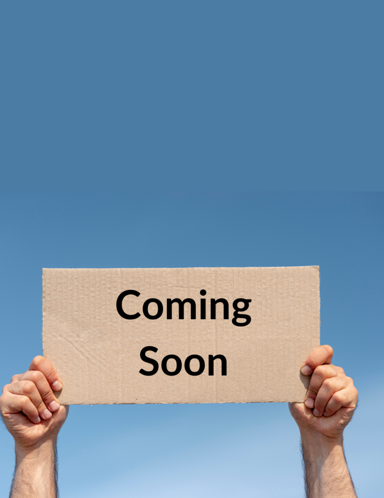 A pair of hands holding a cardboard sign that says "coming soon."